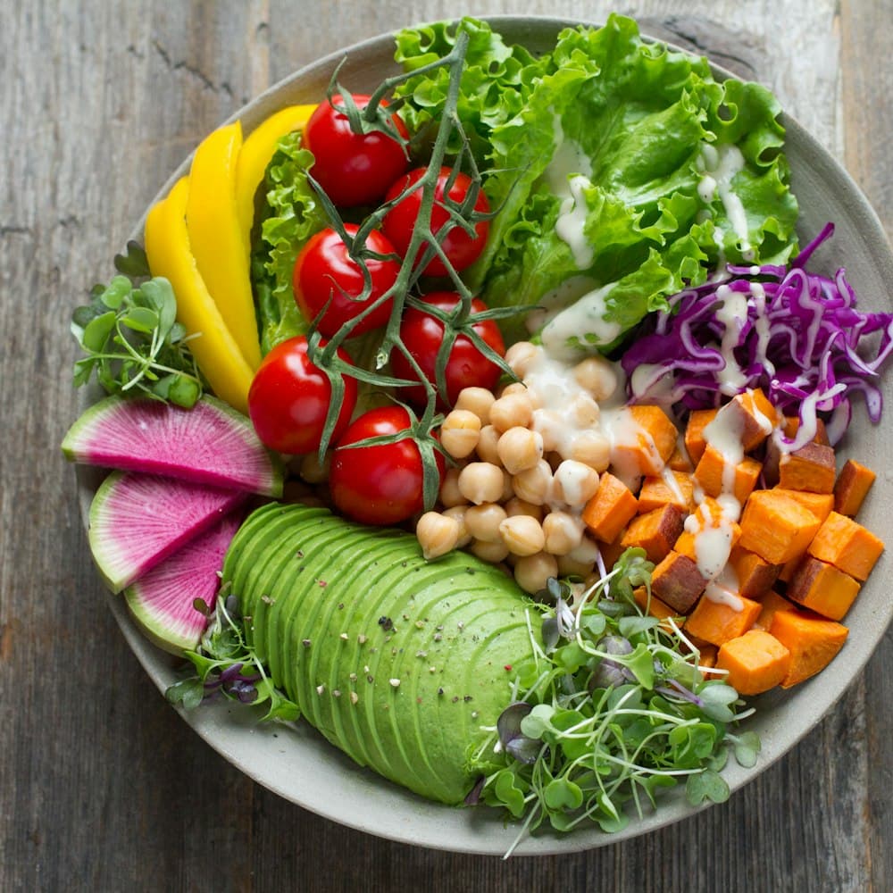 A colourful salad bowl with chickpeas, avocado, tomatoes and fresh greens
